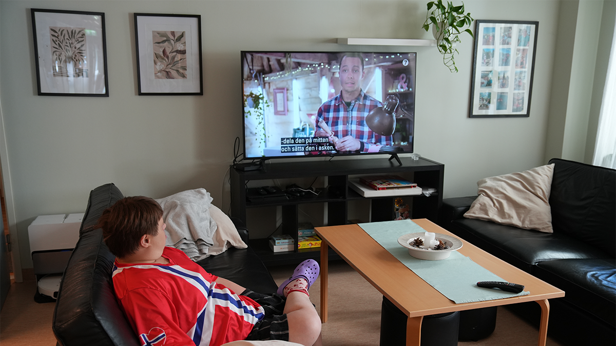 En person tittar på TV halvliggande i en soffa. 