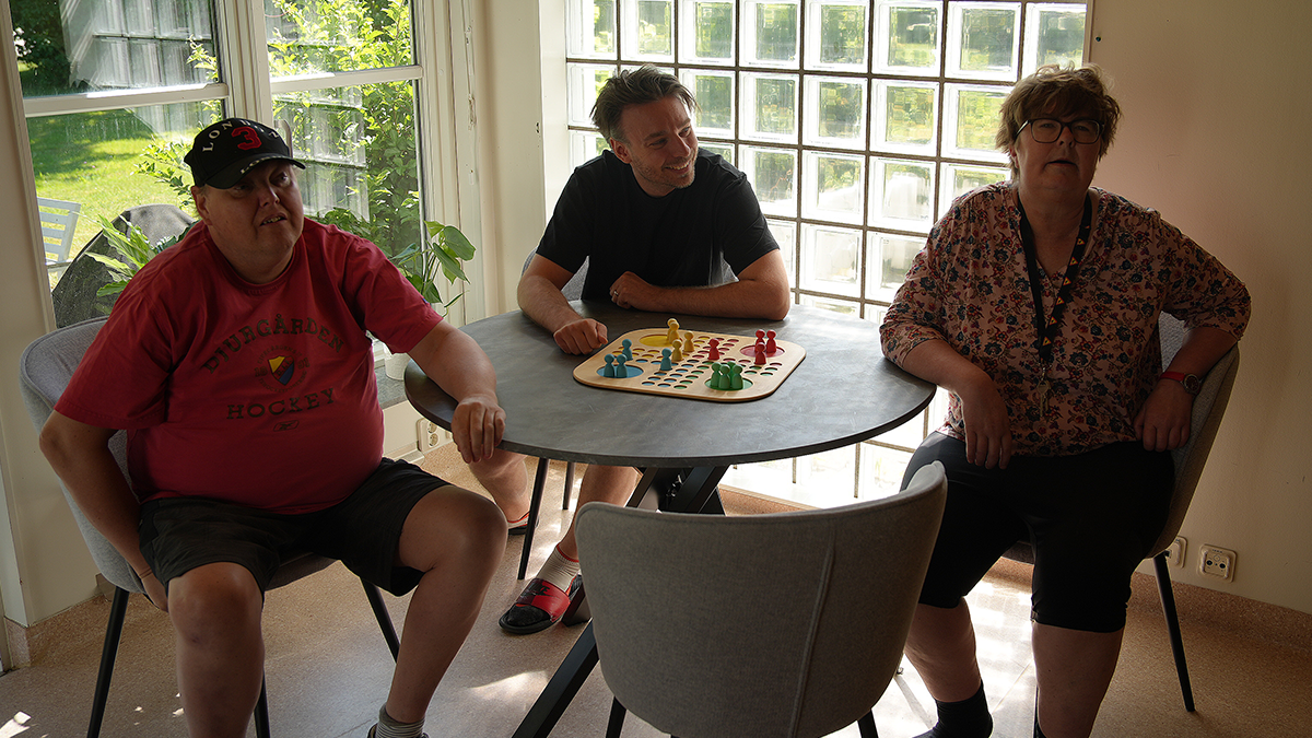 Tre personer omkring ett bord spelar Fyra i rad. 