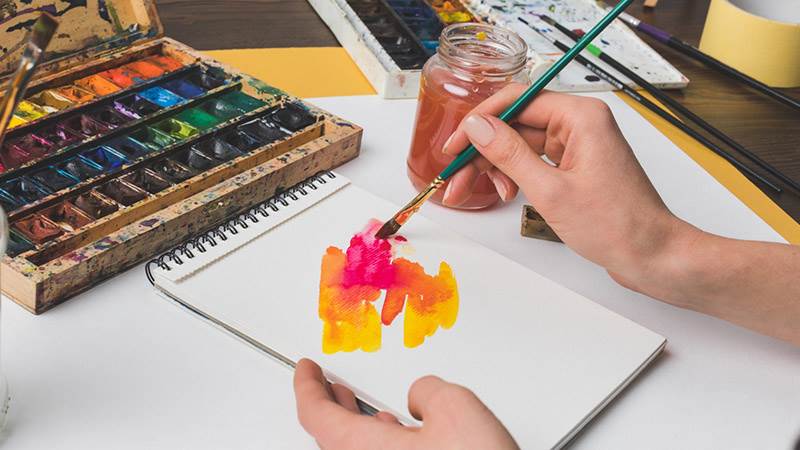 En person som målar med vattenfärg på ett papper