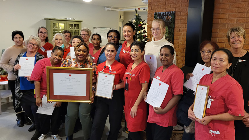 Ett gäng personer står uppradade på en scen med diplom