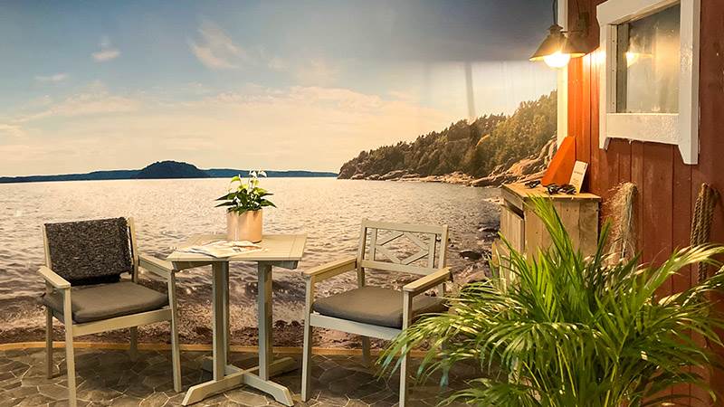 Sinnesrummet på Terrassens vård- och omsorgsboende Två trädgårdsstolar står inomhus framför en vägg som är tapetserad med skärgårdstema