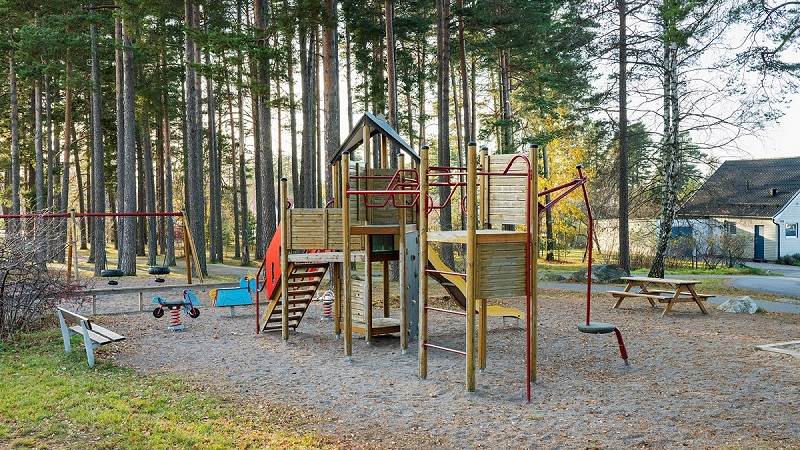 Klenaparkens lekpark vid sidan av höga tallar. Klenaparkens lekpark.