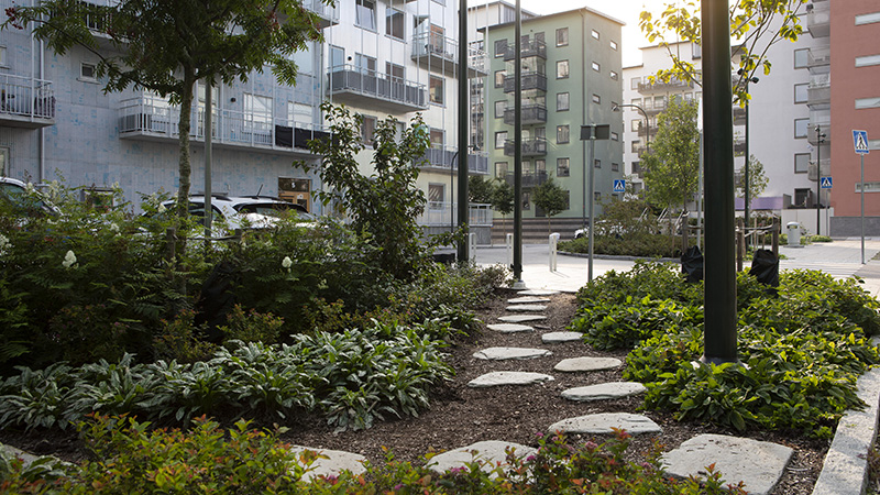 Liten parkyta med växtlighet och gångplattor i sten