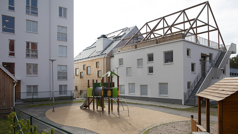 Lekplats med klätterställning och taksiluetter