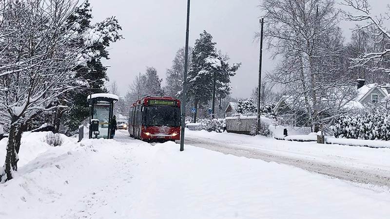 Buss i snöfall längs snöig väg