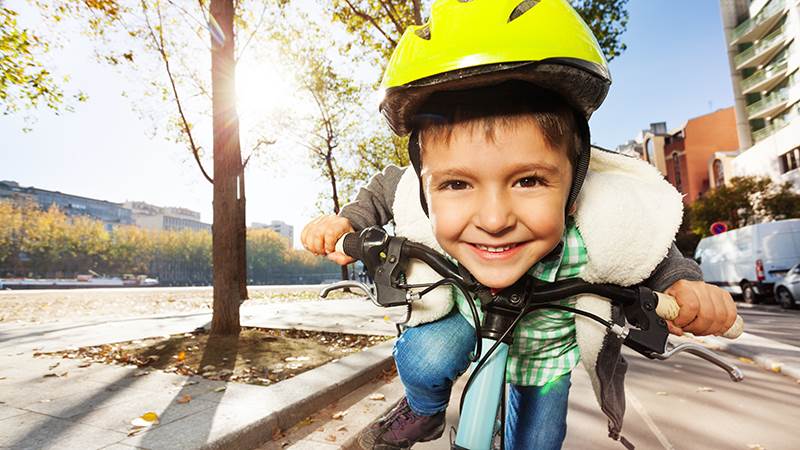 Glad pojke med cykelhjälm på en cykel