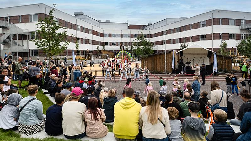 Gatuorkestern Storstan Street Brass och dansföreningen JUDS uppträder på invigningen av Vega skola och aktivitetshus. Publik sitter utanför Vega skol aoch aktivitetshus och ser på musik- och dansframträdande