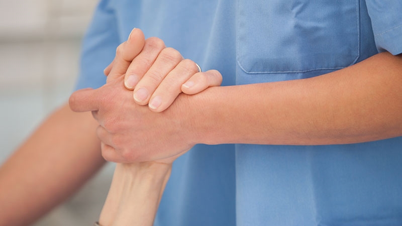 Vårdpersonal håller en patients hand