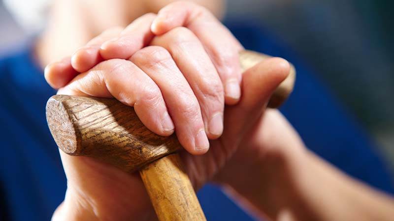Äldre persons hand som håller i en käpp