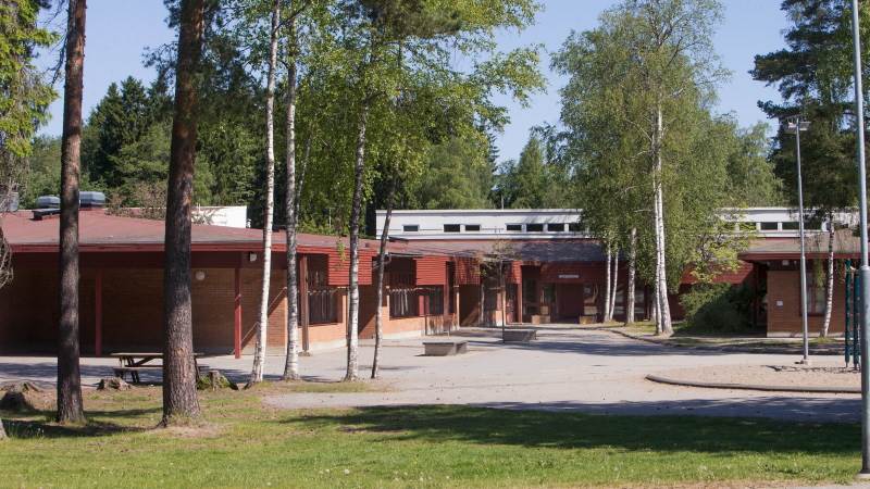 En skolbyggnad i rött tegel och röd träpanel