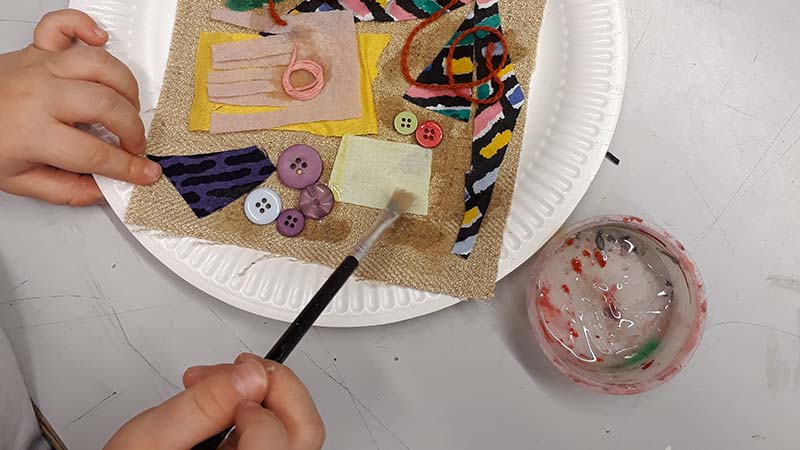 Barnhänder arbetar med textilcollage.