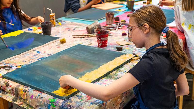 Flicka sitter och målar.