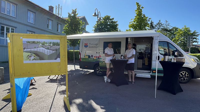 Två män som står vid ett bord framför en husbil.