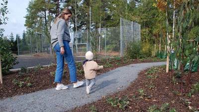 Litet barn och mamma promenerar igenom planteringen på Lillgårdens lekplats