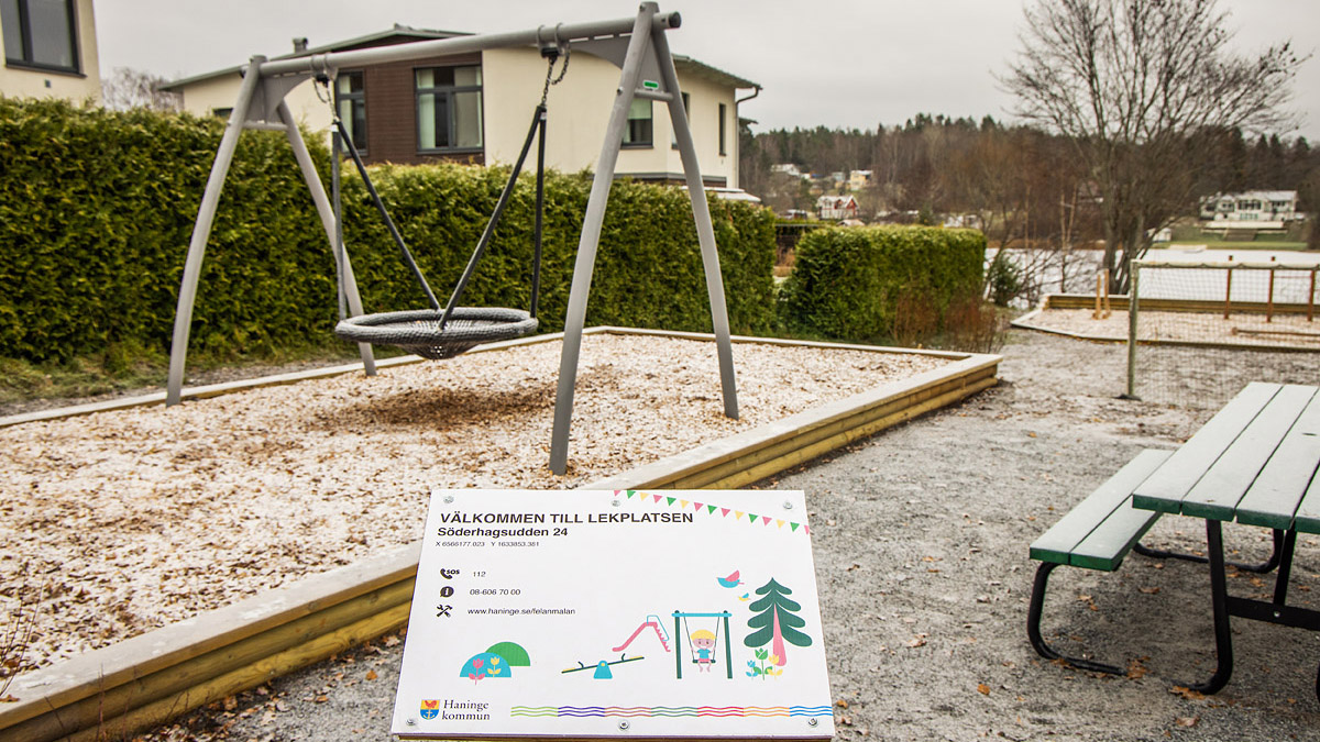 Gunga som står i sand men ett hus bakom