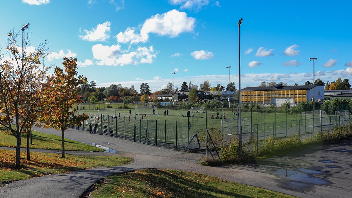 Fotbollsplan med barn som spelar fotboll och publik