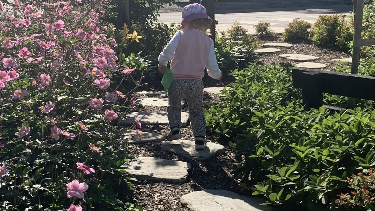 Barn som går på stenplattor som ringlar sig fram omgärdat av grönska i en liten fickpark.