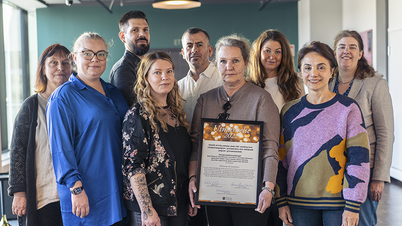 Nio män och kvinnor poserar med diplom