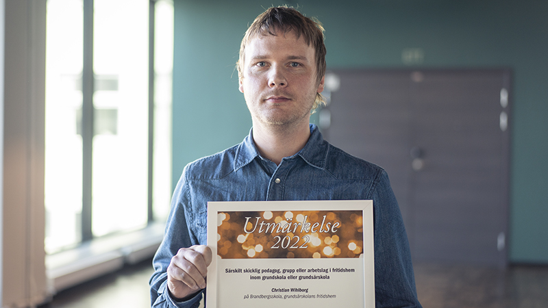 En man i jeansskjorta håller ett diplom