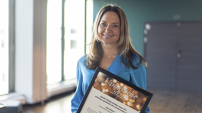 Glad man i blå kostym med ett diplom