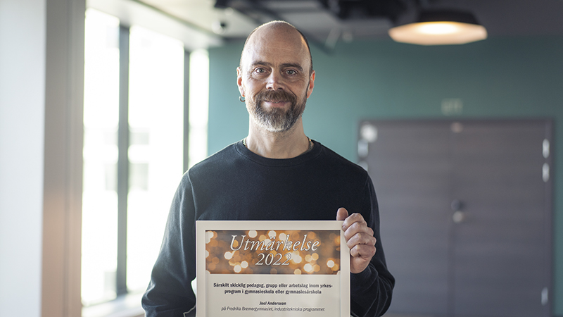 En glad man håller ett diplom