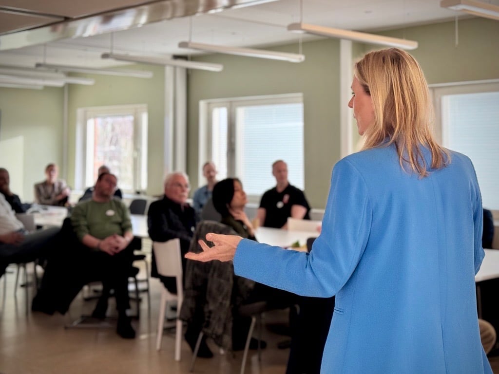 Näringslivschef Katarina Barter i förgrunden, i blå kavaj, framför åhörare sittandes vid ett långsmalt bord.