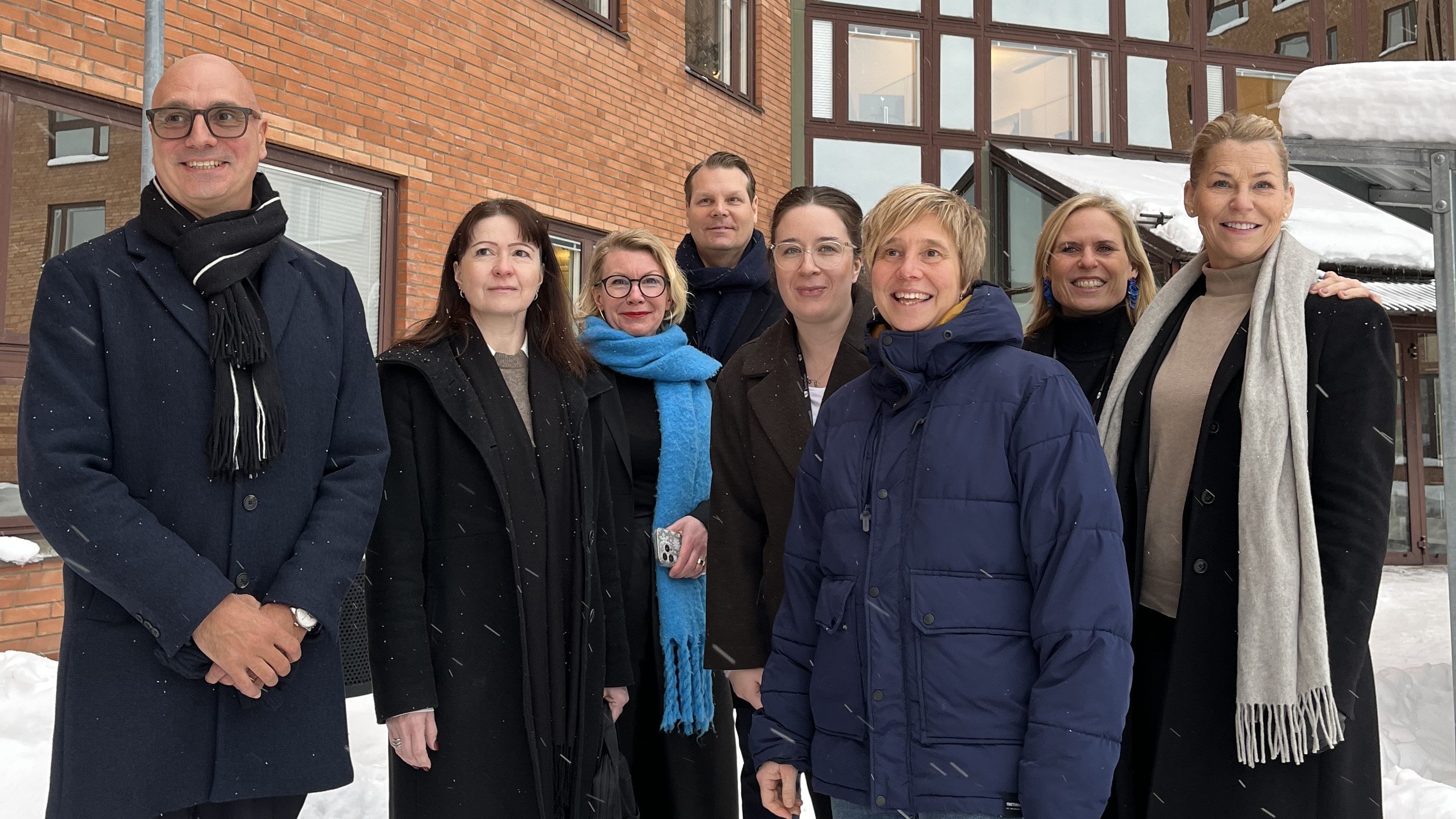 Åtta chefer fotade i grupp framför kommunhuset i vinterväder