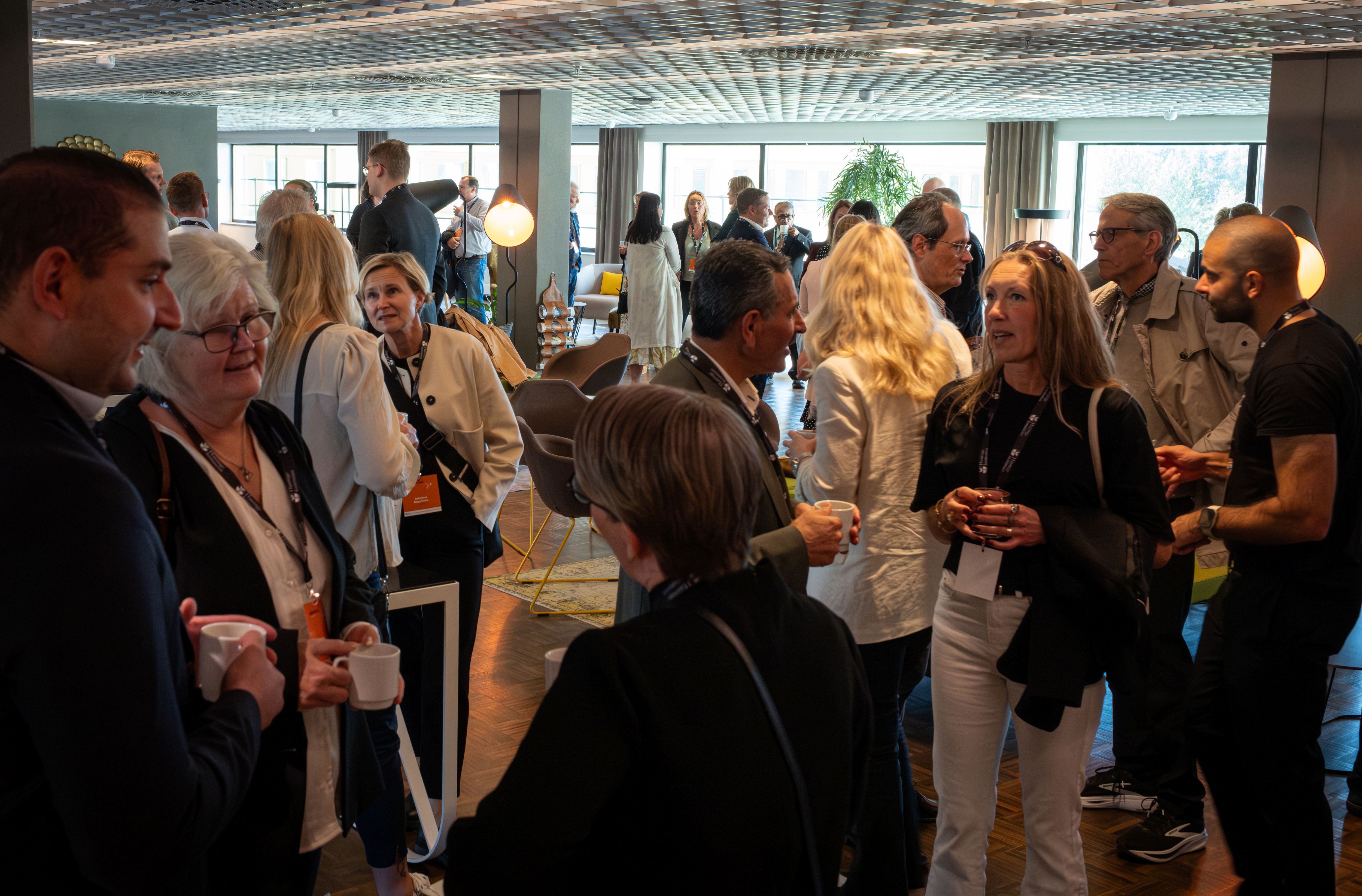 Minglande människor i inomhusmiljö, samtal, leenden.