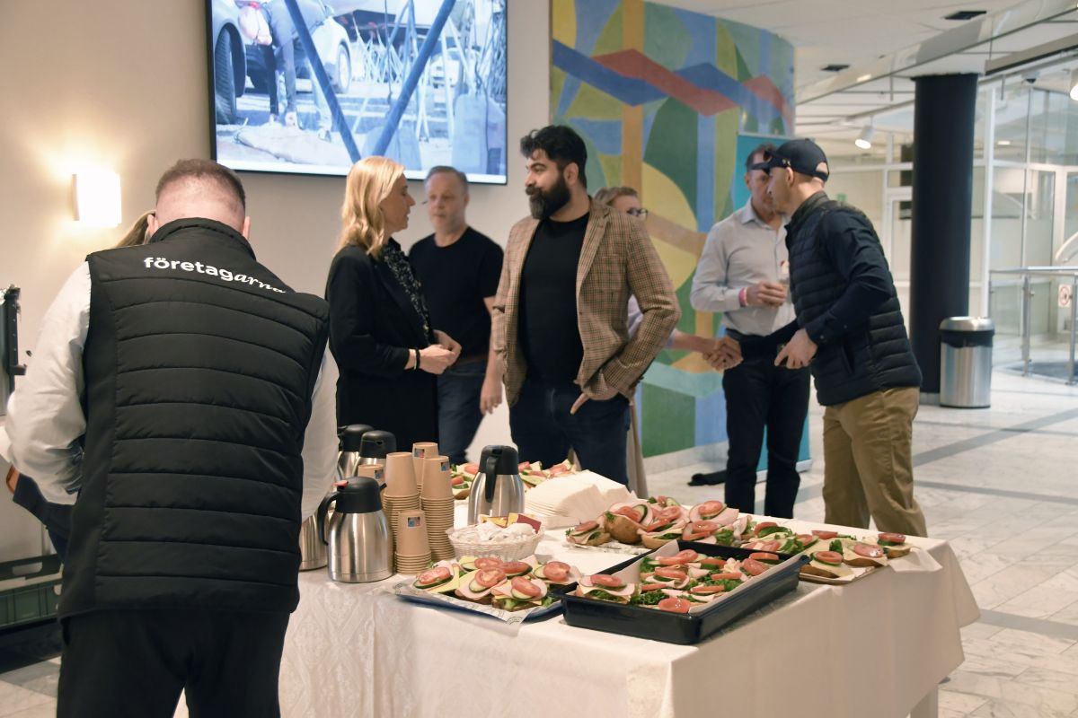 Kaffe och smörgås uppdukat, flera personer i samtal