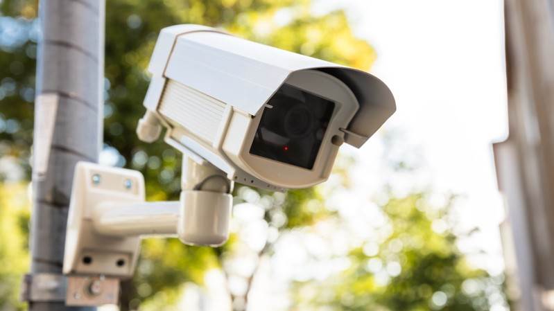 Övervakningskamera med grön växtlighet i bakgrunden