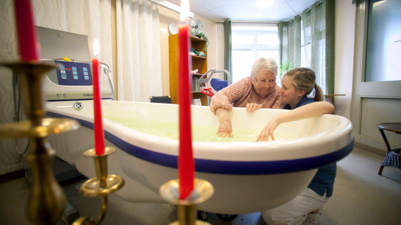 En äldre kvinna och en sköterska känner på vattnet i ett slags badkar på Johanneslunds vård- och omsorgsboende