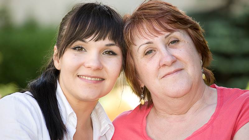 Hemtjänst En yngre och en äldre kvinna tittar in i kameran
