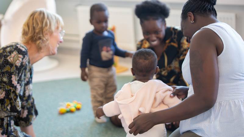 Personal sitter på golvet och leker med två familjer
