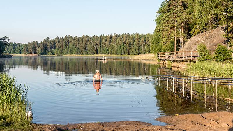 Äldre kvinna på väg ner i vattnet för att bada