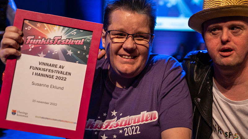 Susanne Eklund håller upp sitt diplom och ler mot kameran.