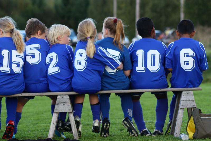 Barn som sitter på en bänk på en fotbollsplan