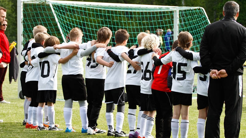 Ett fotbollslag för barn står och håller varandra om ryggen efter en match