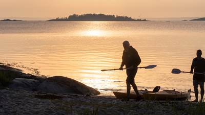 Två personer drar iland sina kajaker i solnedgången