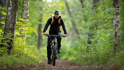 Man som cyklar i skogen