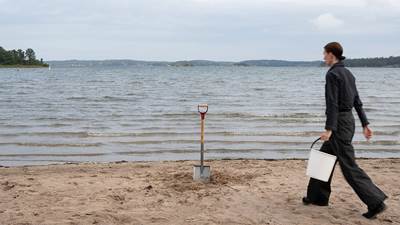 Massrörelser Kvinna med hink och spade på en strand.