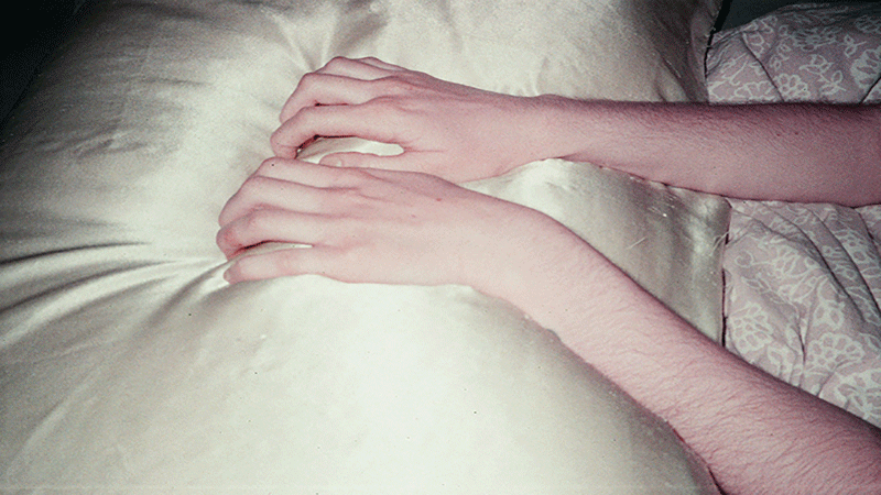 There was a wound; we dwelled Två armar ligger på ett täcke, fotograferade i stillhet. Bilden ingår i konstutställningen "There was a wound; we dwelled".