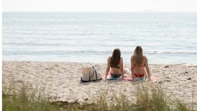 Flickor sitter på sandstrand på Nåttarö