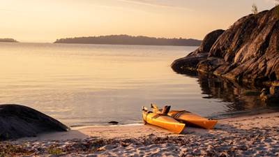 Solnedgång över Nåttarö. Kajaker i strandkanten i solnedgång på Nåttarö.
