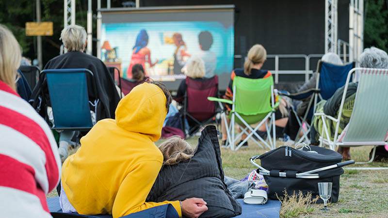 Ett par som ligger på gräset och tittar på utomhusbio