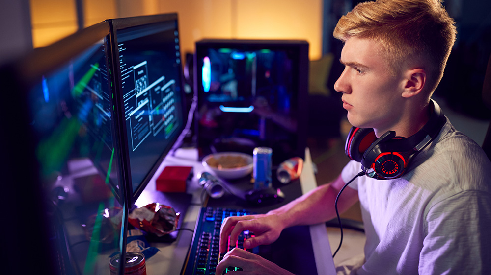 Tonårspojke sitter vid dator.