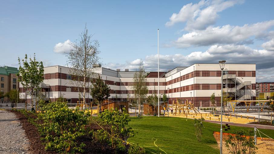 Stort hus med flera våningar och grön park utanför.